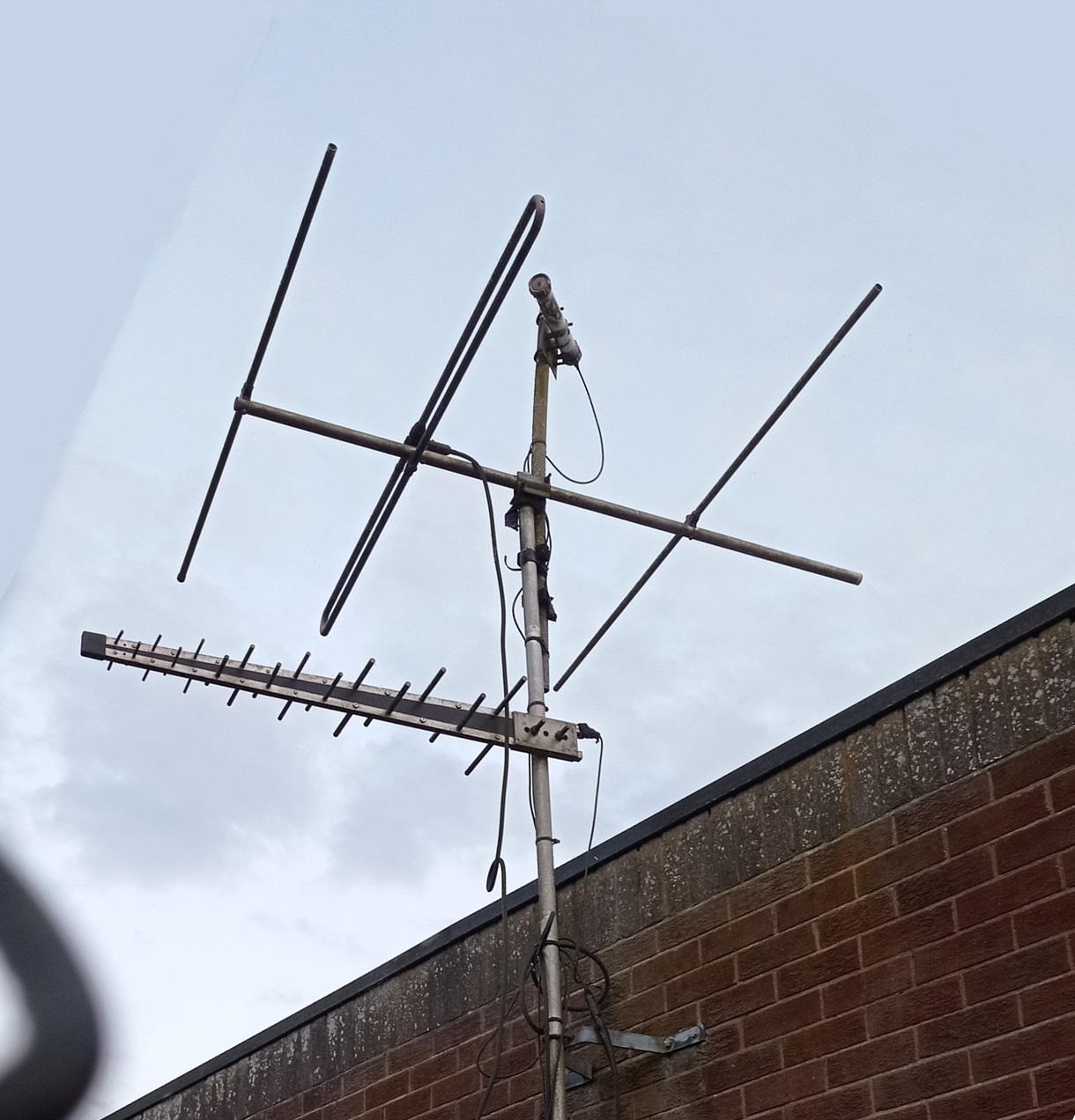 A small antenna mast on the side of a building, carrying a UHF log-periodic, a VHF yagi-uda, and what appears to be a shrouded SHF yagi-uda.